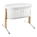 A BabyBjörn Cradle in White with a light natural wood frame and silver metal support legs, shown on a plain white background.