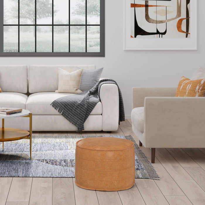 Tan leather round pouf accent stool in modern living room setting - Simpli-Home